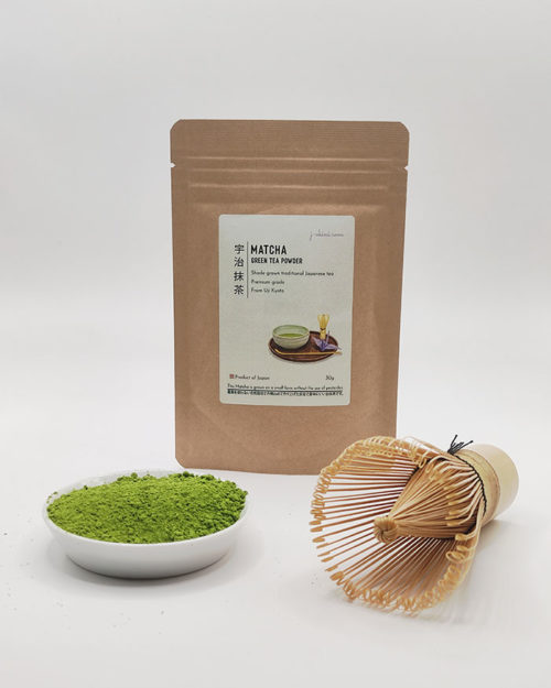 Premium grade Japanese Matcha powder displayed in a dish with a bamboo whisk, in front of J-okini’s 30g Matcha package. Pesticide-free and perfect for traditional tea, Matcha lattes, and sweets. Available at j-okini.com in Malta