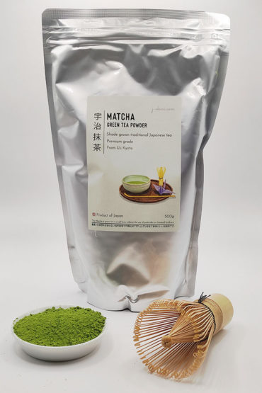 Premium grade Japanese Matcha powder displayed in a dish with a bamboo whisk, in front of J-okini’s 500g Matcha package. Pesticide-free and perfect for traditional tea, Matcha lattes, and sweets. Available at j-okini.com in Malta