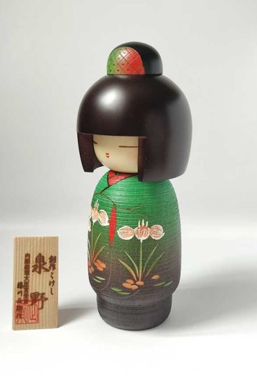 A modern creative Kokeshi doll, Izumino (泉野), by award-winning artist Fujikawa Shoei wears a beautiful kimono in elegant green tones with blooming Japanese irises. Available at j-okini.com in Malta