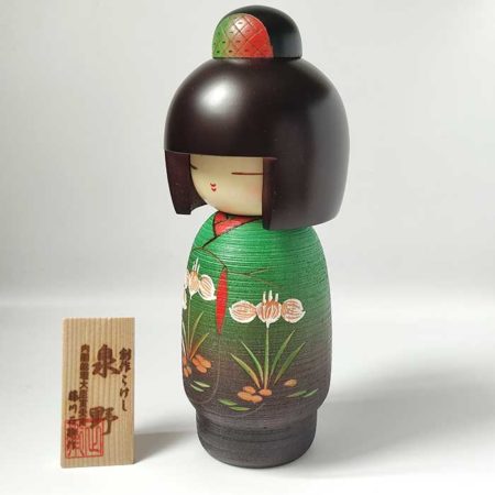 A modern creative Kokeshi doll, Izumino (泉野), by award-winning artist Fujikawa Shoei wears a beautiful kimono in elegant green tones with blooming Japanese irises. Available at j-okini.com in Malta