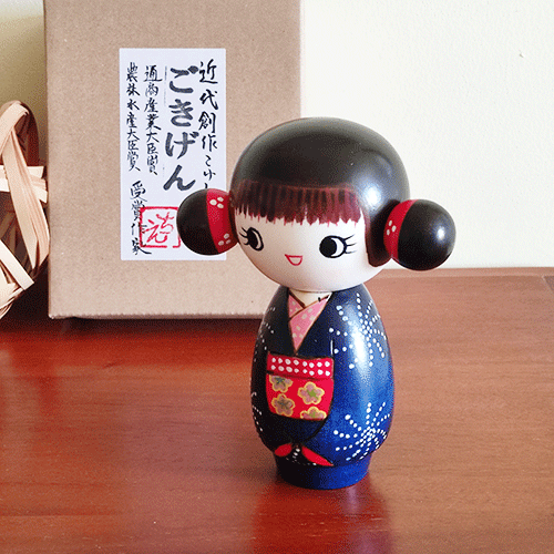 This 近代創作こけし modern creative Kokeshi doll is called 'ごきげん - Gokigen' and it was created by an award-winning artist 'ちえ Chie'. The doll's feature would be the space buns.  Her pretty Kimono has a design of Hanabi (fire works) and the obi (wide sash) has a contrast colour red. Available at j-okini.com Malta