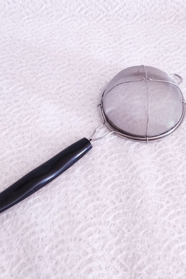 Matcha-tea-sifter with a brown handle