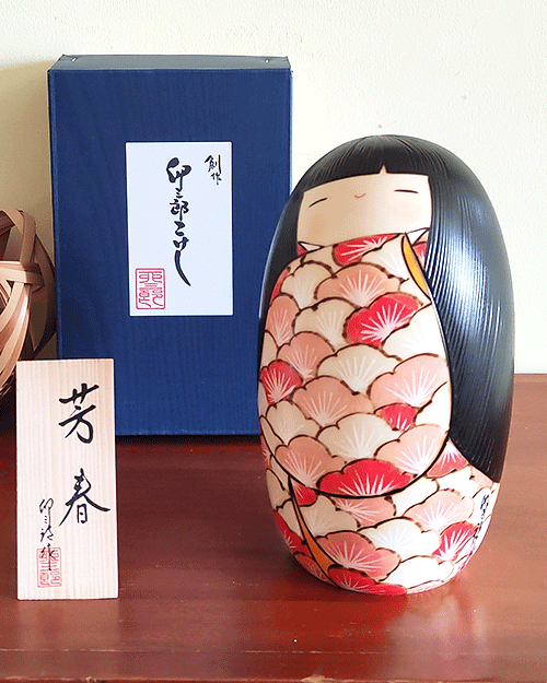 Crafted by the renowned artist 卯三郎 Usaburo, the '芳春 Houshun' Kokeshi doll embodies the essence of spring with its fragrance and beauty. This award-winning piece showcases a kimono adorned with vibrant Ume (Plum blossoms), each petal painted to capture the delicate shades of vermilion, symbolizing the diversity and unity found in nature. The heart of each blossom is highlighted in white, reflecting the warmth of spring, while the doll's elegantly curved hair adds a touch of grace. '芳春 Houshun' is not just a doll; it's a celebration of the season's eternal beauty, inviting you to embrace the charm and elegance of Japanese art and culture. Available at j-okini Malta