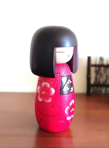 Japanese Benitsubaki Kokeshi doll with intricate camellia flower designs in red and white, symbolizing elegance and nobility in Japanese culture.. Available at j-okini.com in Malta Europe