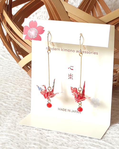 Crafted with meticulous attention to detail, these earrings feature a 3cm piece of Chiyogami, a traditional Japanese washi paper, known for its vibrant and intricate designs. Each pair is carefully sealed with three layers of protective coating to ensure durability and shine. At the heart of these earrings is the motif of the Tsuru, the Japanese word for crane. Revered in Japanese culture, the Tsuru is celebrated as a symbol of peace and longevity, embodying wishes for prosperity and health. These earrings are not only a testament to unique craftsmanship but also carry a deep cultural significance. The design is complemented by a delicate red glass bead, harmonizing beautifully with the pink Chiyogami paper to create a piece that is both eye-catching and meaningful.