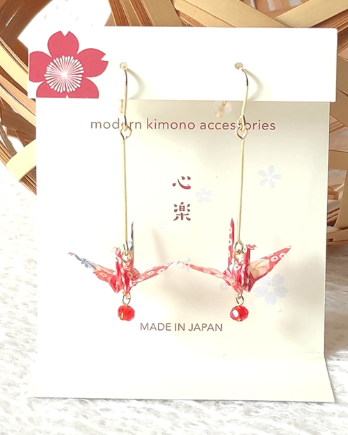 Crafted with meticulous attention to detail, these earrings feature a 3cm piece of Chiyogami, a traditional Japanese washi paper, known for its vibrant and intricate designs. Each pair is carefully sealed with three layers of protective coating to ensure durability and shine. At the heart of these earrings is the motif of the Tsuru, the Japanese word for crane. Revered in Japanese culture, the Tsuru is celebrated as a symbol of peace and longevity, embodying wishes for prosperity and health. These earrings are not only a testament to unique craftsmanship but also carry a deep cultural significance. The design is complemented by a delicate red glass bead, harmonizing beautifully with the pink Chiyogami paper to create a piece that is both eye-catching and meaningful.