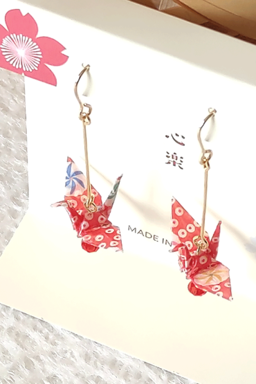 Crafted with meticulous attention to detail, these earrings feature a 3cm piece of Chiyogami, a traditional Japanese washi paper, known for its vibrant and intricate designs. Each pair is carefully sealed with three layers of protective coating to ensure durability and shine. At the heart of these earrings is the motif of the Tsuru, the Japanese word for crane. Revered in Japanese culture, the Tsuru is celebrated as a symbol of peace and longevity, embodying wishes for prosperity and health. These earrings are not only a testament to unique craftsmanship but also carry a deep cultural significance. The design is complemented by a delicate red glass bead, harmonizing beautifully with the pink Chiyogami paper to create a piece that is both eye-catching and meaningful.