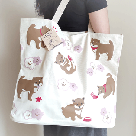 A large white tote bag with a cute Shiba Inu and Sakura (cherry blossom) design. This tote bag is lightweight, has a zipper, and has a small pocket on the inside, so it can be used in a variety of situations. Available at j-okini in Malta