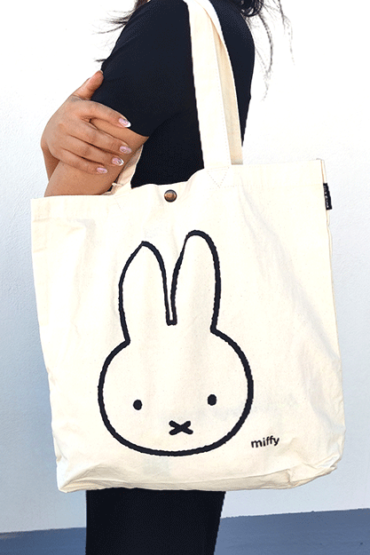 Miffy's slim canvas tote bag in white with a large Miffy illustration in black. button closure tote bag. Spacious tote bag. Japanese tote bag. Availabe at j-okini.com in Malta