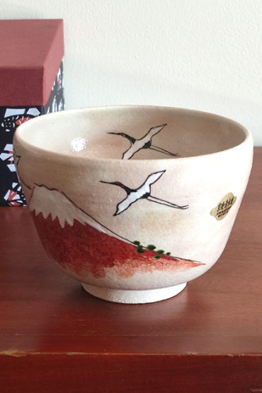 Handcrafted Kiyomizu-ware Matcha bowl featuring Red Fuji and crane design on a warm beige background with soft pink and orange speckles.. Gift idea from j-okini.com in Malta