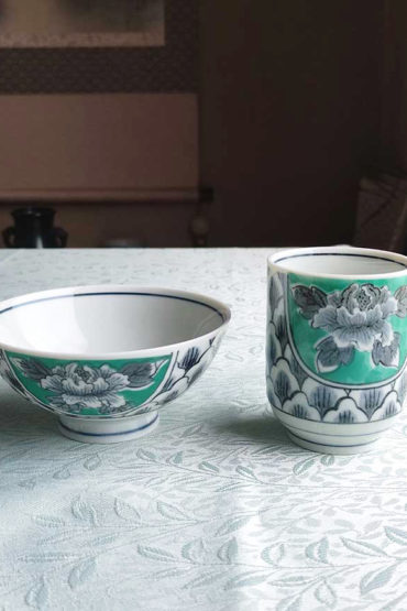 Banko-yaki Yunomi tea cup and rice bowl set featuring bold peony flowers with a vivid green background framed by traditional details, crafted by the Aigama kiln in Yokkaichi, Japan. Available at j-okini.com in Malta.