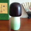 Handcrafted Japanese Kokeshi doll 'Chouchou' by artist Fujikawa Shoei, featuring a light green Michiyuki kimono jacket with a butterfly and pink floral design. Available at j-okini.com in Malta