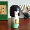 Handcrafted Japanese Kokeshi doll 'Chouchou' by artist Fujikawa Shoei, featuring a light green Michiyuki kimono jacket with a butterfly and pink floral design. Available at j-okini.com in Malta