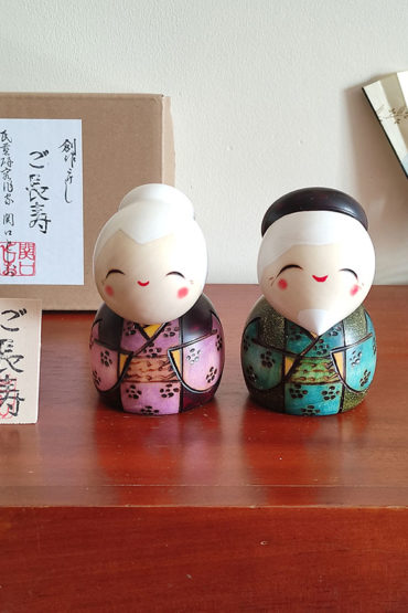 A modern Creative Kokeshi doll set named 'Gochouju' by award-winning artist Sekiguchi Toshio. The dolls depict an elderly couple with kind smiles, dressed in elegant kimono, celebrating longevity and happiness. Handcrafted in Japan. Available at j-okini.com in Malta