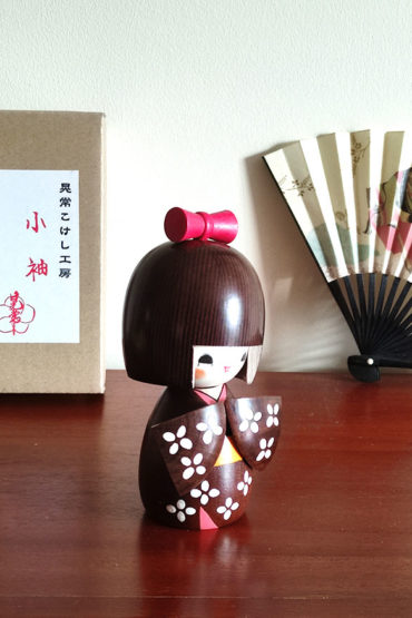 Handcrafted Japanese Kokeshi doll 'Kosode' by artist Kojo, wearing a chic brown kimono with a soft pink collar and a vibrant yellow obi. Available at j-okini.com in Malta