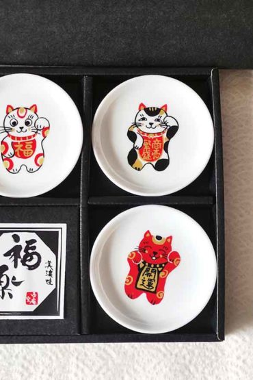 A set of five Japanese Maneki-Neko small dishes, each featuring a unique beckoning cat design symbolizing luck, protection, happiness, prosperity, and wealth. Perfect for serving soy sauce or condiments. Made in Japan. Available at j-okini.com in Malta