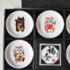 A set of five Japanese Maneki-Neko small dishes, each featuring a unique beckoning cat design symbolizing luck, protection, happiness, prosperity, and wealth. Perfect for serving soy sauce or condiments. Made in Japan. Available at j-okini.com in Malta