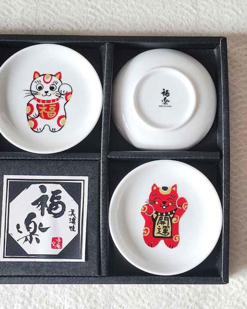 A set of five Japanese Maneki-Neko small dishes, each featuring a unique beckoning cat design symbolizing luck, protection, happiness, prosperity, and wealth. Perfect for serving soy sauce or condiments. Made in Japan.
