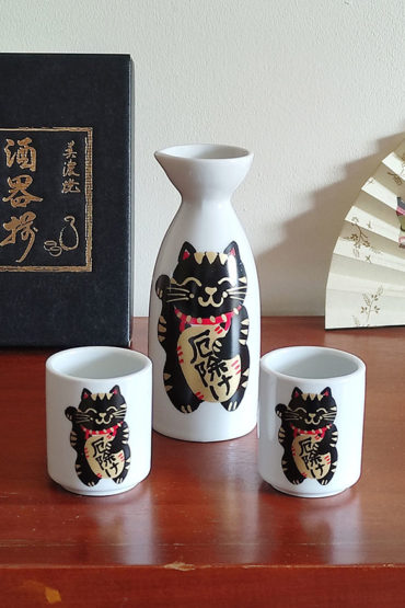 Mino ware porcelain sake set featuring a black Maneki Neko with a smiley face, symbolizing protection and good fortune. Available at j-okini.com in Malta