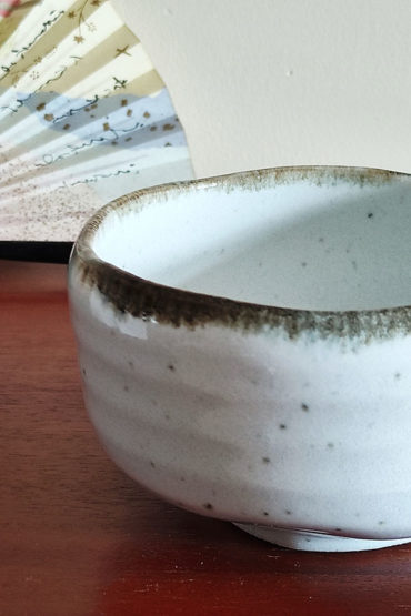 Mino ware Matcha bowl with a white glaze that enhances the green of Matcha, a winding dark green-brown rim, and a wabi-sabi aesthetic, handcrafted in Japan Available at j-okini.com in Malta