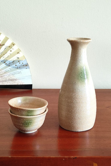 A glazed Kiseto Sake Set with a beige tokkuri bottle and matching sake cups, each featuring soft green accents and a smooth, speckled finish. Made in Japan. Available at j-okini.com in Malta