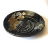 Black porcelain plate with a spiral-carved surface and gold and silver painted Tsubaki Camellia – part of a seasonal Japanese Mino-yaki plate set. Available at j-okini.com in Malta
