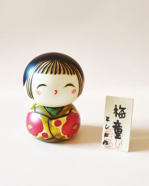 Ume Warabe Kokeshi doll by Toshio – green kimono with red plum blossoms. Buy it online at j-okini.com in Malta