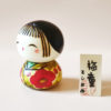 Close up of Ume Warabe Kokeshi’s smiling face and delicate plum blossom kimono