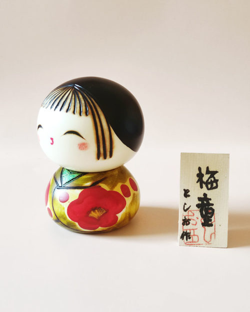 Close up of Ume Warabe Kokeshi’s smiling face and delicate plum blossom kimono