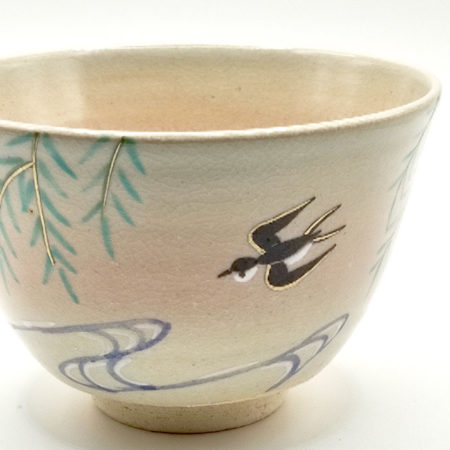close up to Kiyomizu-ware matcha bowl “Yanagi to Tsubame” by Kahou Nakamura, featuring willow tree, sparrow in flight, flowing waves, gold details, and natural Gohonte patterns.