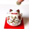 Smiling Japanese Maneki Neko piggy bank decorated with Daruma and lucky Tai fish