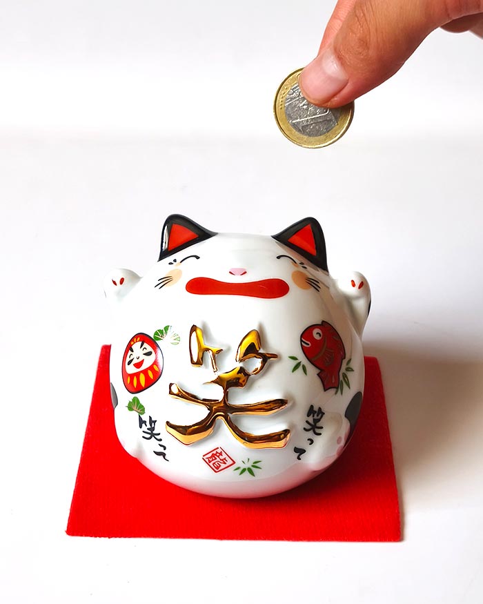 Smiling Japanese Maneki Neko piggy bank decorated with Daruma and lucky Tai fish