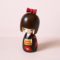 Hana Tsubaki Japanese wooden kokeshi doll by Kojo wearing a black kimono with red camellias and a gold obi.