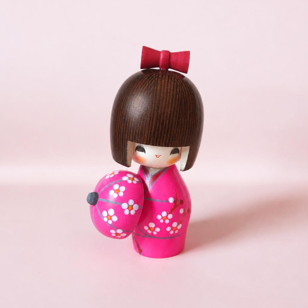 Haru Urara Japanese wooden kokeshi doll by Kojo wearing a pink floral kimono and holding a matching Japanese umbrella.