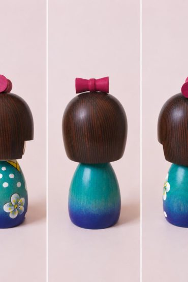 Koyuki-chan Japanese wooden kokeshi doll by Kojo wearing a blue kimono with white flowers and a red bow.