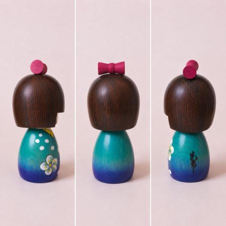 Koyuki-chan Japanese wooden kokeshi doll by Kojo wearing a blue kimono with white flowers and a red bow.