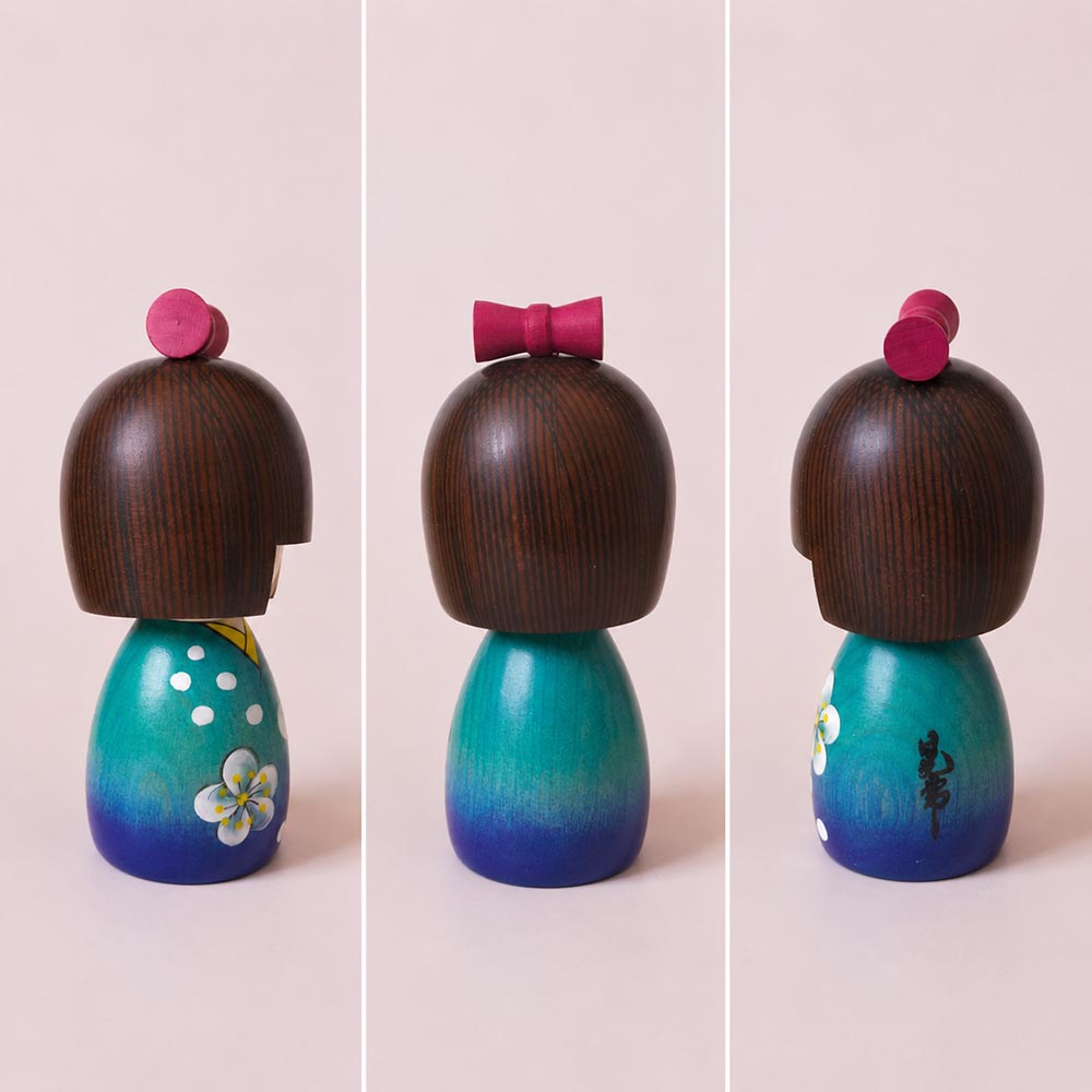koyuki-chan-2 Koyuki-chan Japanese wooden kokeshi doll by Kojo wearing a blue kimono with white flowers and a red bow.