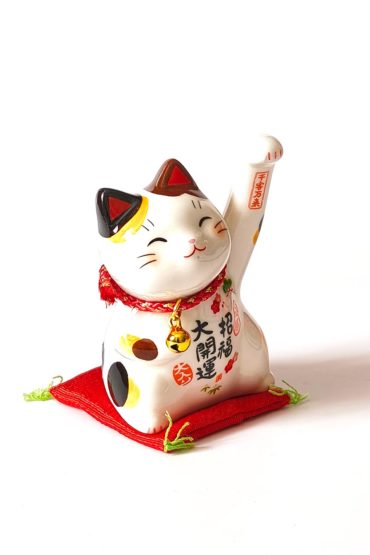Small Japanese ceramic Maneki Neko lucky cat with raised paw, bell, colourful decorations and red cushion. Buy it on j-okini.com in Malta (Europe)