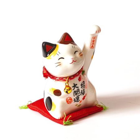 Small Japanese ceramic Maneki Neko lucky cat with raised paw, bell, colourful decorations and red cushion. Buy it on j-okini.com in Malta (Europe)